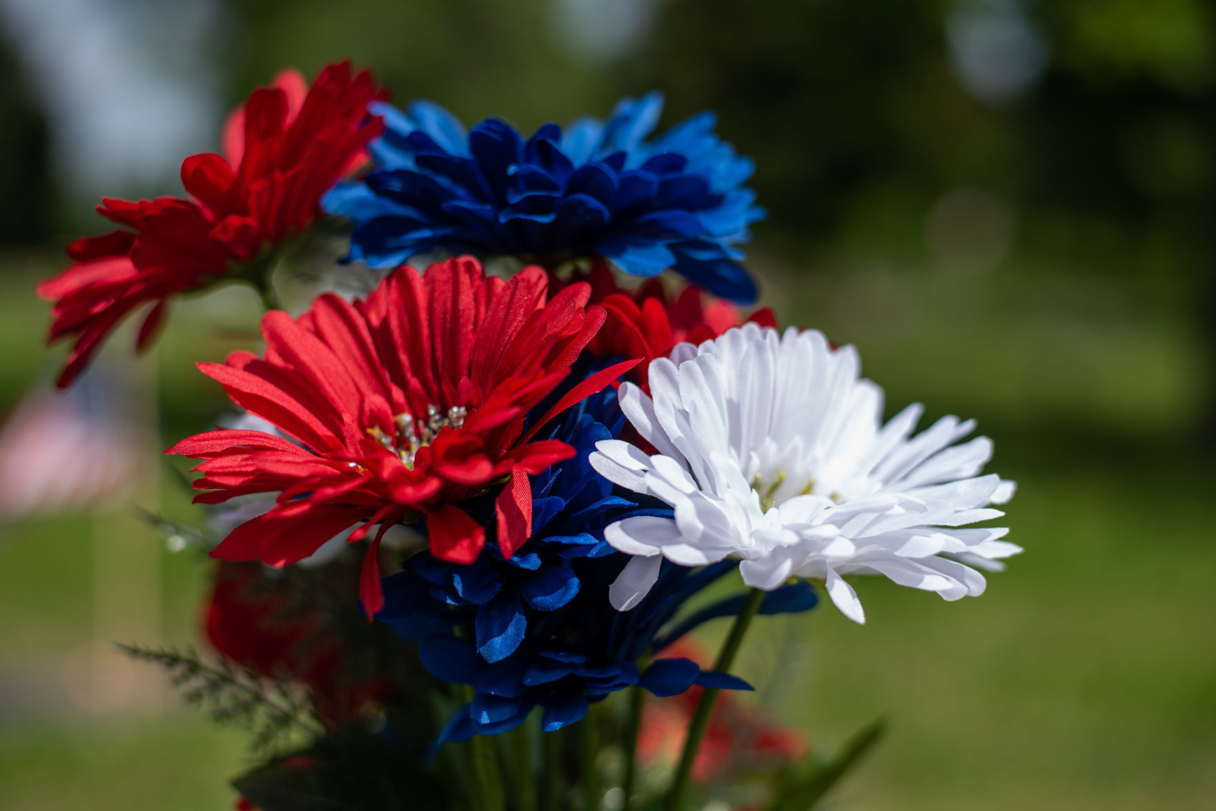 A bouquet of red, white and blue flowers sit next to a headstone at Valley View Memorial Park on Saturday.